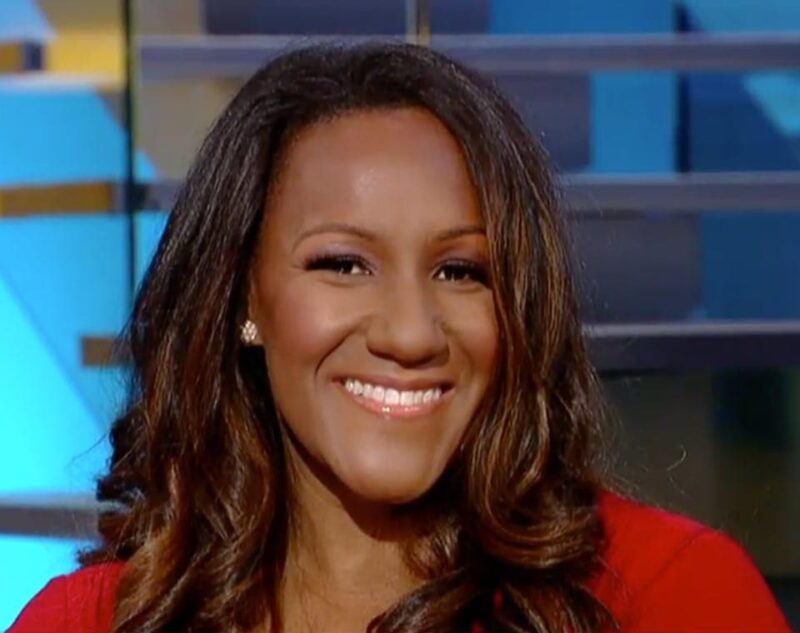 Smiling woman with long brown hair, wearing a red top, against a blurred background with blue and yellow tones.