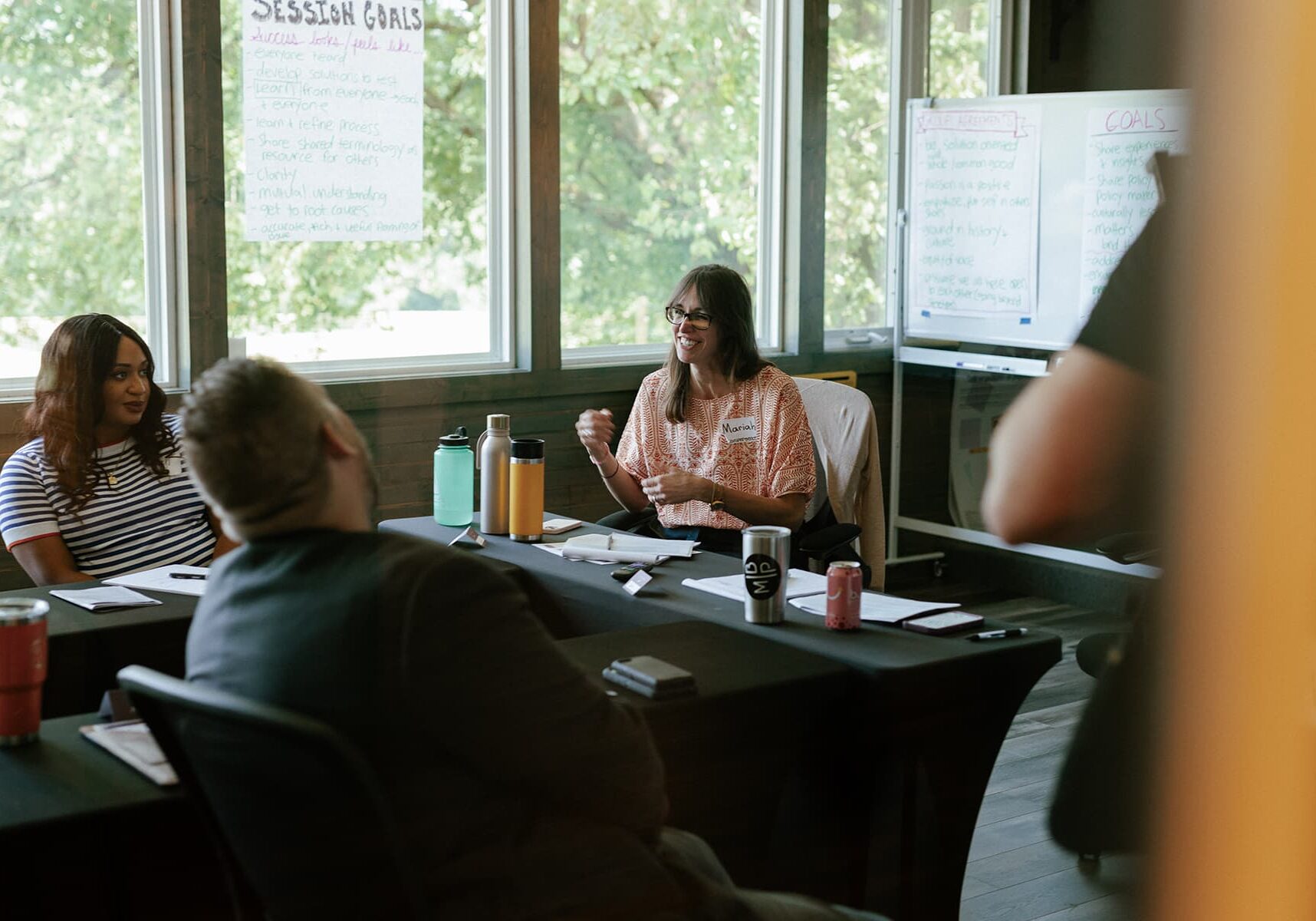 People in a meeting with whiteboards detailing session goals.