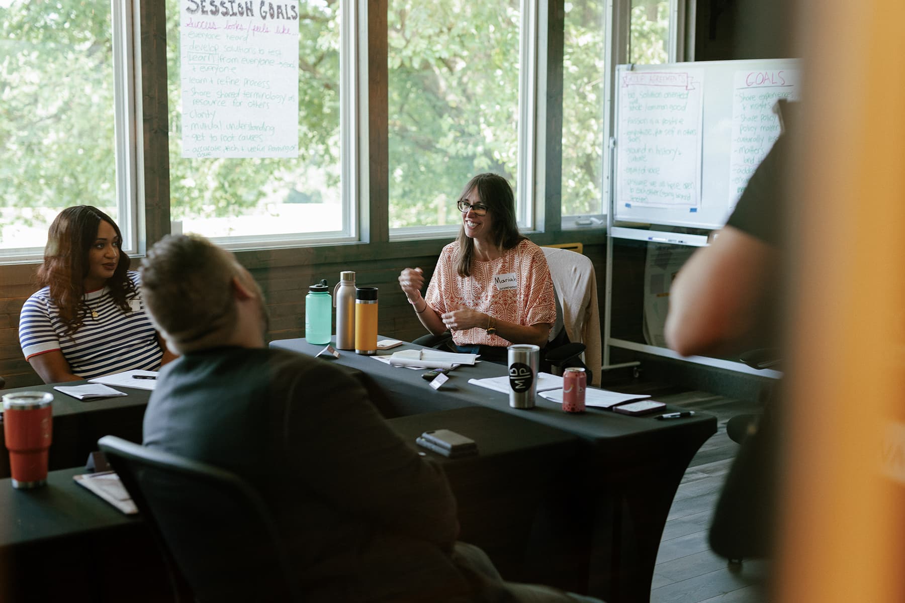 People in a meeting with whiteboards detailing session goals.