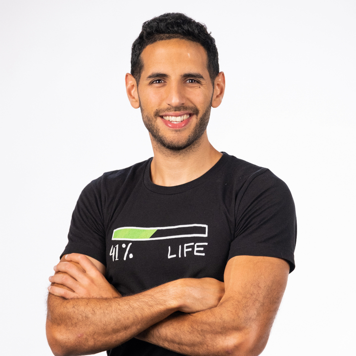 Man with short dark hair and beard smiles, arms crossed, wearing a black t-shirt with a progress bar graphic and "41% LIFE" text. White background.