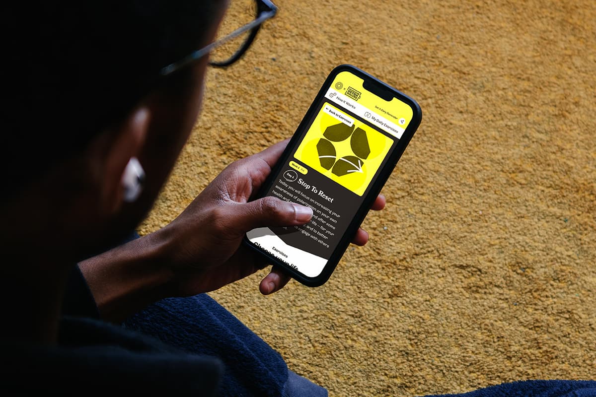 A young man sitting on a couch with a phone in hand, exploring the Polarization Detox Challenge app.